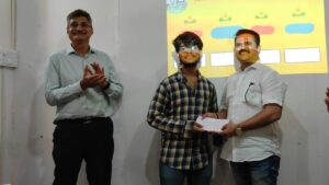 A group of four people is celebrating the announcement of winners, with Abhinav receiving a prize.