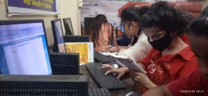 A young girl combining bookwork with computer learning at CSC pod, showing a balance between two modes of studying.